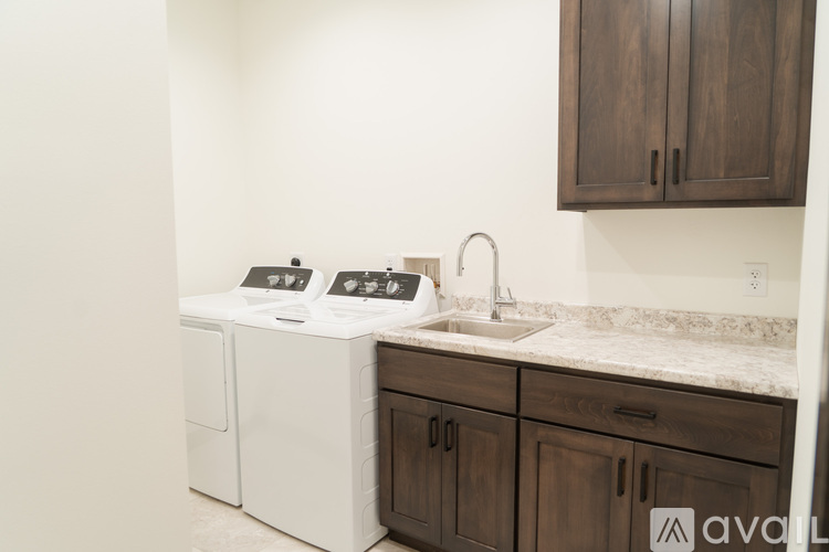 A kitchen with a white dishwasher and brown cabinets.