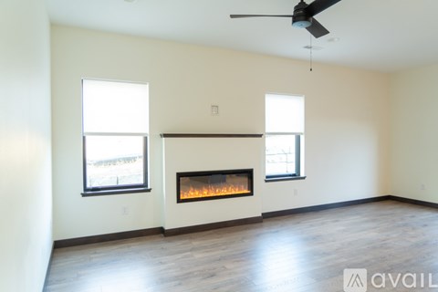 A living room with a fireplace and two windows.