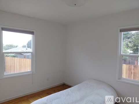 A bedroom with a large bed and two windows.