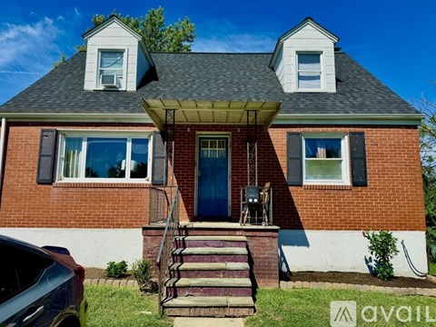 A red brick house with a blue door and a covered porch.