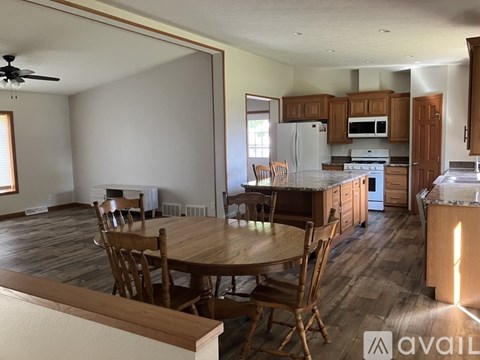 A kitchen with a table and chairs in the foreground and a refrigerator, microwave, and oven in the background.