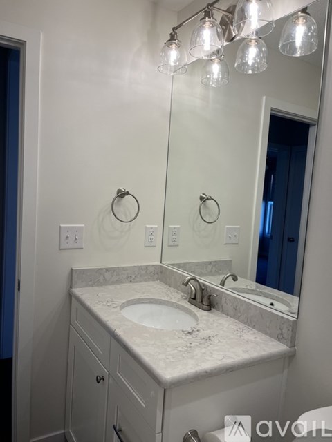 A bathroom with a sink, mirror, and lights.
