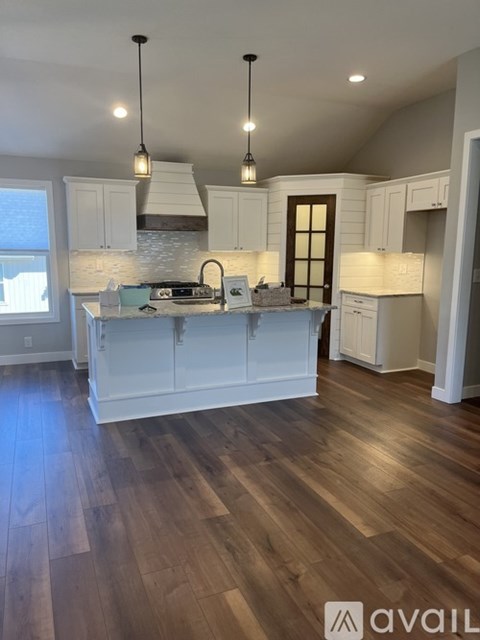 A kitchen with white cabinets and a wooden floor.