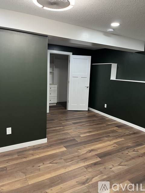 A room with a white door and wooden flooring.