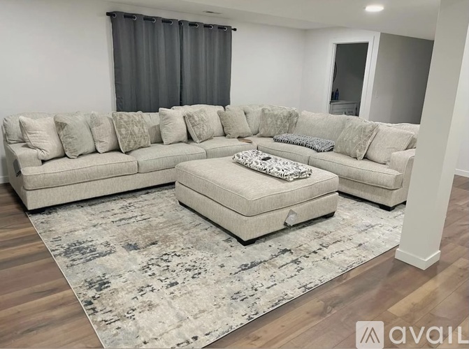 A large sectional sofa with a chaise lounge and ottoman in a living room.
