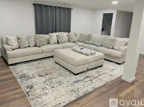 A large sectional sofa with a chaise lounge and ottoman in a living room.