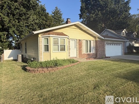 A house with a yellow siding and a brick chimney is for sale.