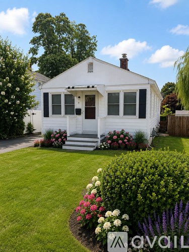 A white house with a garden in front.