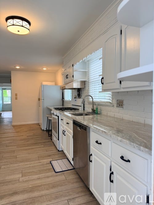 A kitchen with white cabinets and a marble countertop.