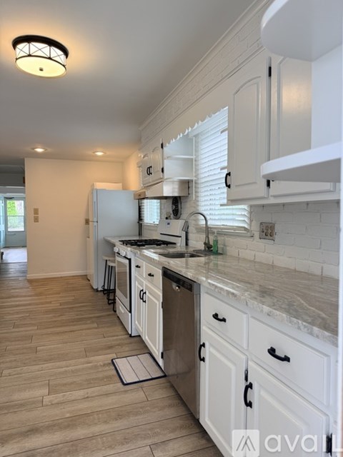 A kitchen with white cabinets and a marble countertop.
