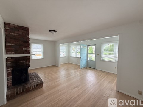 A living room with a fireplace and wooden floors.