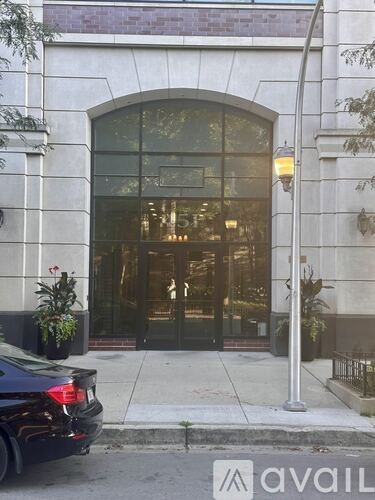 A black car is parked in front of a building with a large glass door.