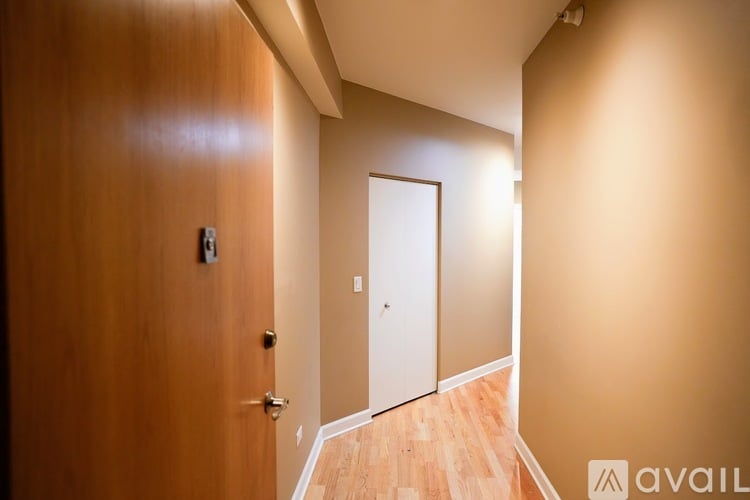 A hallway with a wooden door and a white door at the end.
