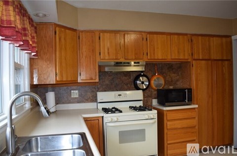 A kitchen with wooden cabinets and a white stove top oven.