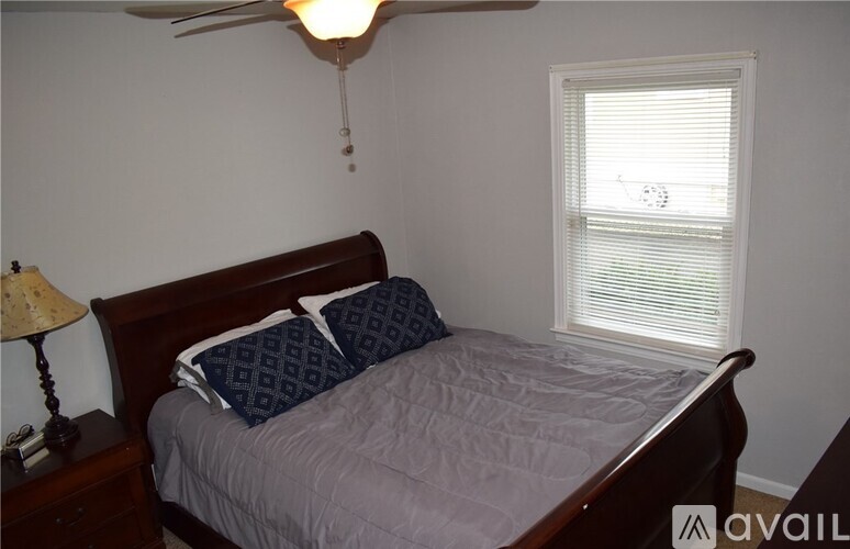 A bedroom with a bed, nightstand, and window.