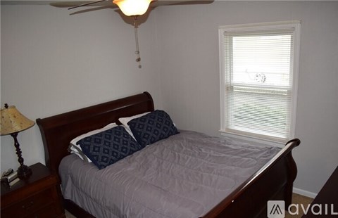 A bedroom with a bed, nightstand, and window.