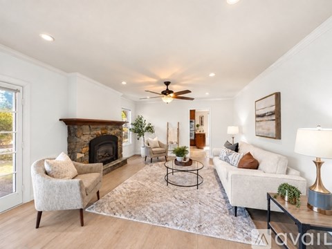 A living room with a fireplace and a ceiling fan.