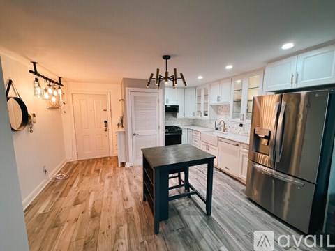 A kitchen with a wooden floor and a table in the middle.