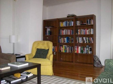 A yellow chair sits in front of a bookshelf filled with books.