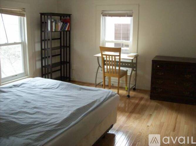 A bedroom with a bed, desk, chair, and bookshelf.
