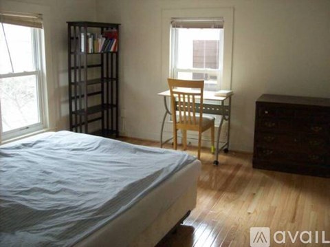 A bedroom with a bed, desk, chair, and bookshelf.