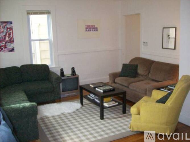 A living room with a green couch, a brown couch, a yellow chair, and a coffee table.