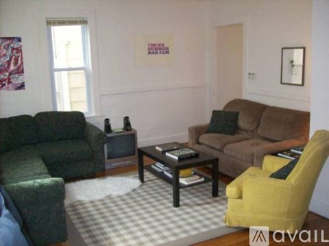 A living room with a green couch, a brown couch, a yellow chair, and a coffee table.