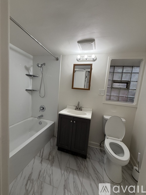 A bathroom with a marble floor, a toilet, a sink, and a bathtub.