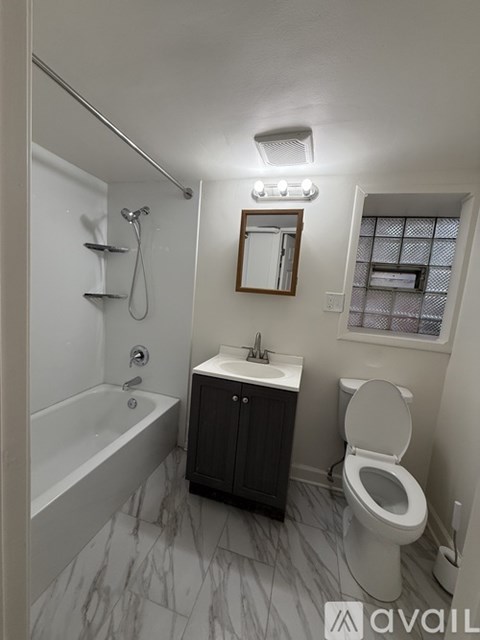 A bathroom with a marble floor, a toilet, a sink, and a bathtub.