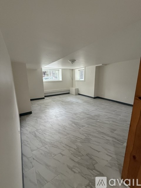 A spacious room with a marble tile floor and white walls.