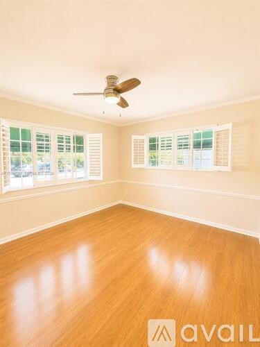 A room with a ceiling fan and wooden flooring.