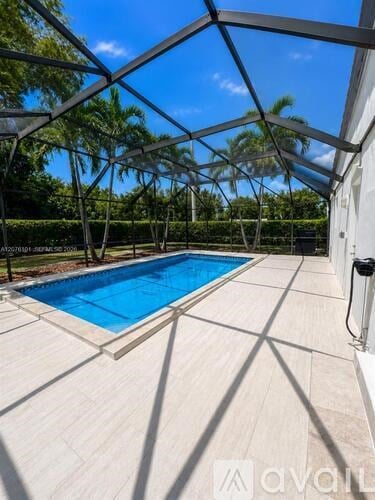 A pool enclosed by a glass ceiling with trees in the background.