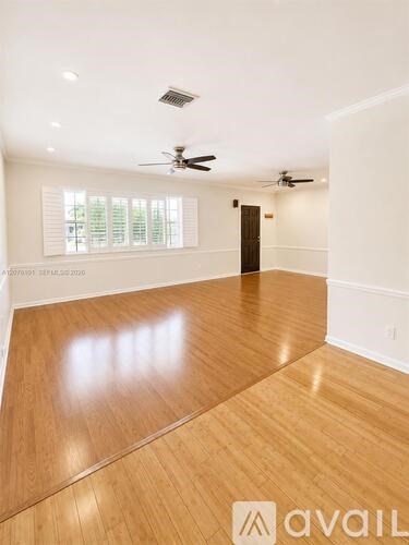 A spacious room with wooden flooring and a ceiling fan.