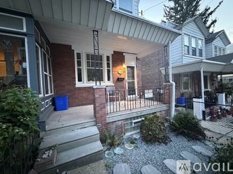 A house with a front porch and a blue trash can.