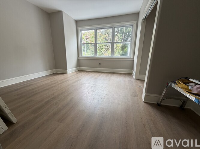 A room with wooden flooring and a window overlooking trees.