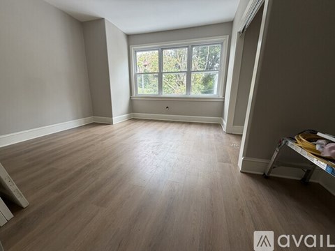 A room with wooden flooring and a window overlooking trees.