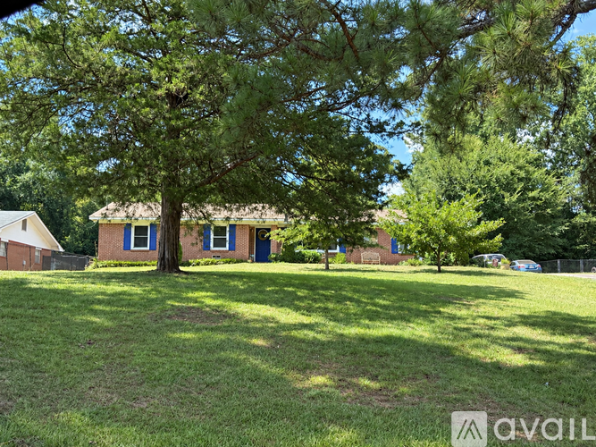 A tree in a grassy area with a house in the background.