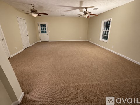 A room with a carpeted floor and a ceiling fan.