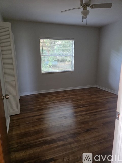 A room with wooden flooring and a window with blinds.