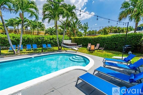 A pool surrounded by palm trees and lounge chairs.