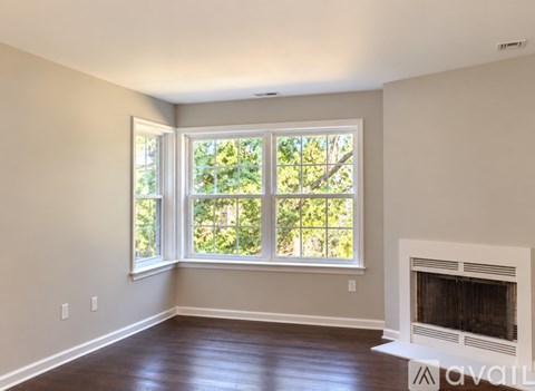 A room with a fireplace and a window with a view of trees.