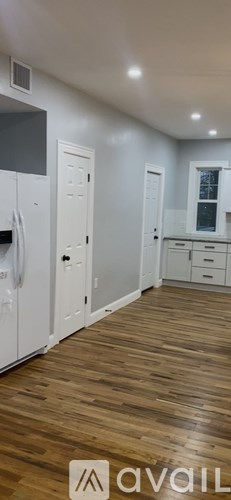 A kitchen with white cabinets and a wooden floor.
