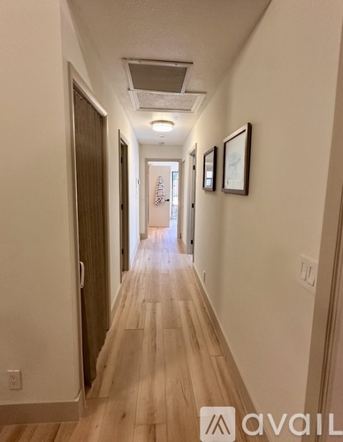 A long hallway with wood floors and white walls.