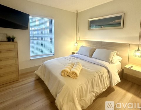 A bedroom with a large bed, a window with blinds, and a painting on the wall.