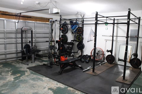 A gym with a weight rack, bench, and weights.
