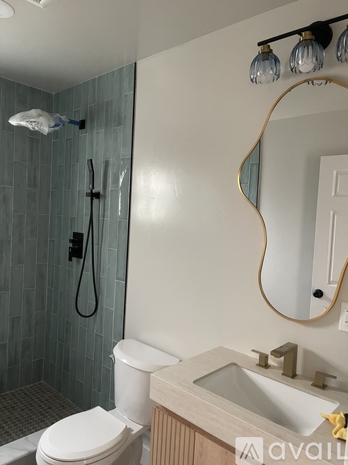 A bathroom with a white toilet, a sink with a gold faucet, and a mirror with a gold frame.