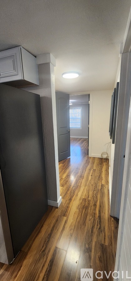 A kitchen with a black refrigerator and wooden floors.