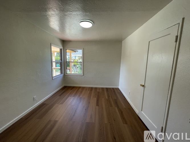 A room with wooden floors and a window with a view of trees.