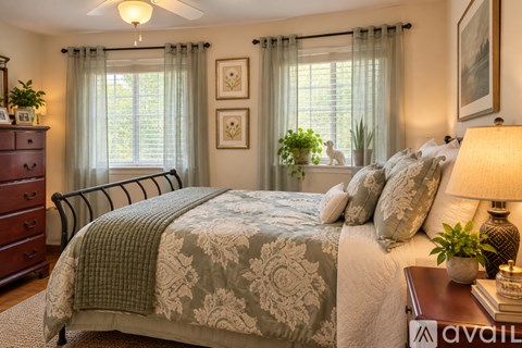 A bedroom with a large bed and a window with curtains.