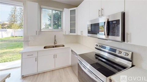 A modern kitchen with white cabinets and stainless steel appliances.